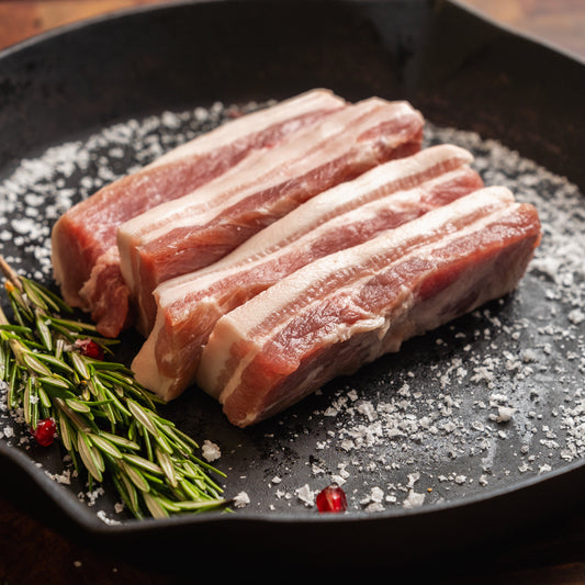 500g pack of boneless, skinless pork belly slices available in Plain, BBQ Plum, and Smokey BBQ flavours in cast iron pan cooking
