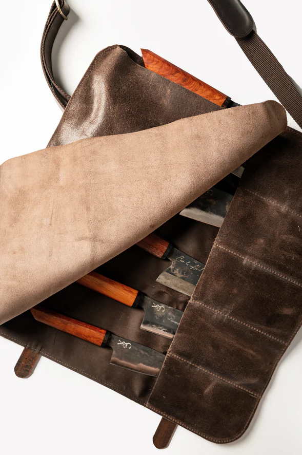 Premium leather knife roll with cotton canvas lining, holds up to six knives, spark-resistant, includes adjustable shoulder strap
